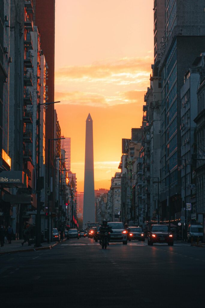 Sunset view of the iconic Obelisco de Buenos Aires with vibrant city lights and urban skyline.